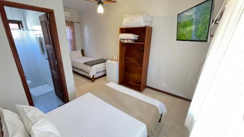 a small room with two beds and a bathroom at Pousada Brisa do Leste in Paraty