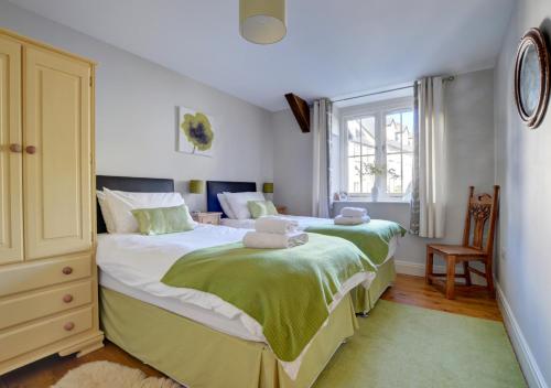 a bedroom with two beds with green and white sheets at The Stables Lynton in Lynmouth