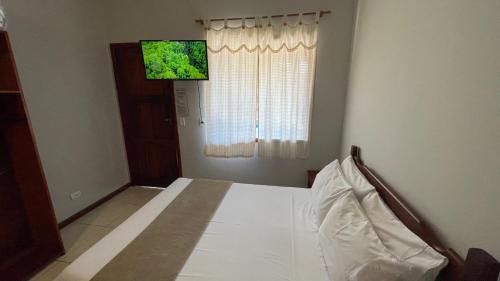 a bedroom with a white bed with a window at Pousada Brisa do Leste in Paraty