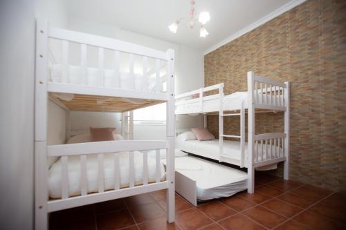 2 literas blancas en una habitación con una pared de ladrillo en Villa las Raices en Sanlúcar de Barrameda