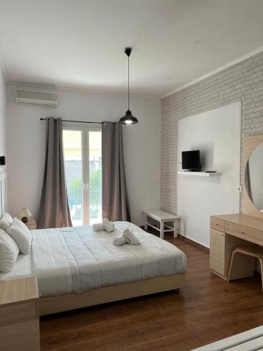 een witte slaapkamer met een bed en een raam bij Olive Grove Poolside Apartments in Benitses