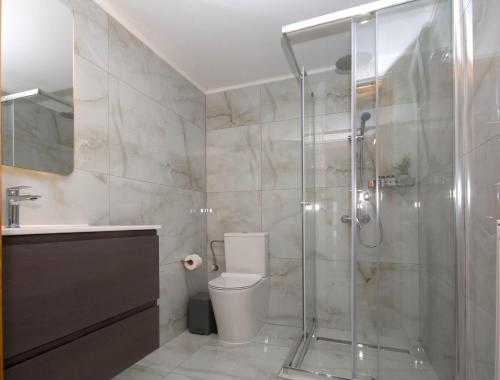 uma casa de banho com um WC e uma cabina de duche em vidro. em Villa Kalliestia, sea view veranda and garden em Kissamos