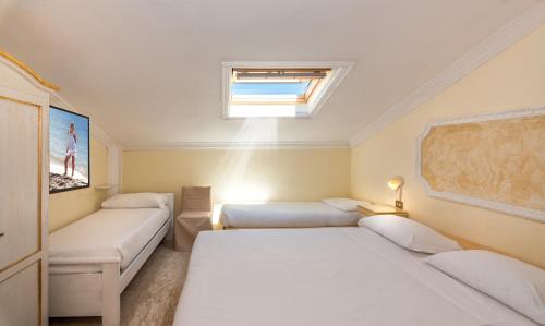 a small bedroom with two beds and a window at Hotel Tahiti in Viareggio