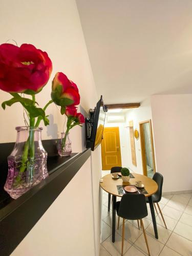 a room with a table and a vase with red roses at Apartmani DA in Piran