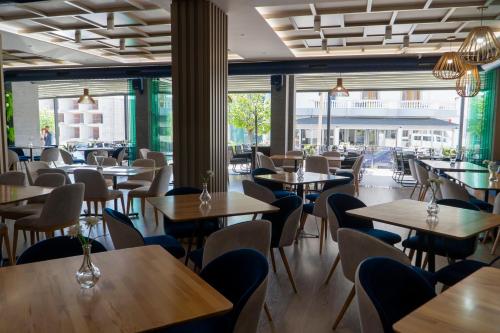 un restaurante con mesas, sillas y ventanas en Hotel Blue Sky, en Sarandë