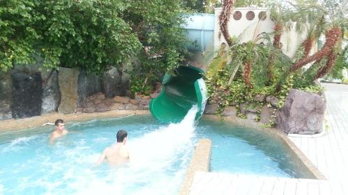 twee personen in een zwembad met een glijbaan bij Het Toeval in Koksijde