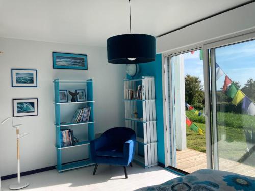 - une chambre avec une chaise bleue et une fenêtre dans l'établissement La Maison Bleue-Sciotot-Les Pieux, aux Pieux