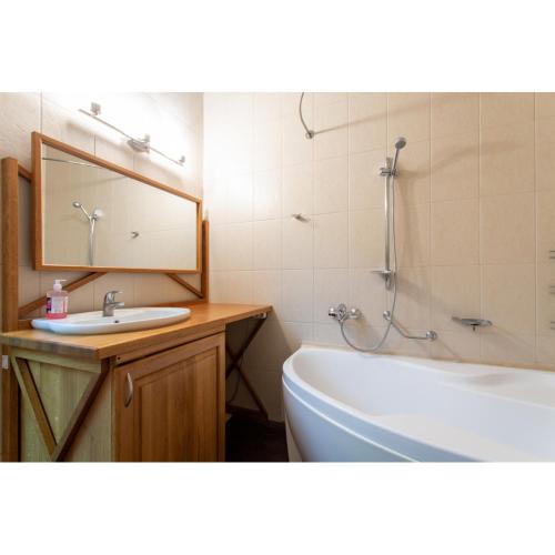 ein Badezimmer mit einem Waschbecken, einer Badewanne und einem Spiegel in der Unterkunft Cozy apartment on Nezalezhnosti Avenue in Kharkov