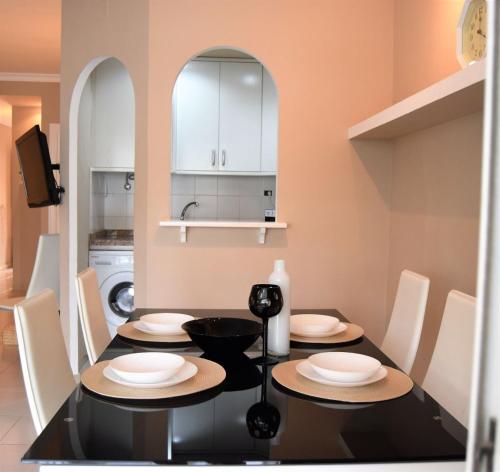 a dining room with a black table and white chairs at CASA AVVA in San Miguel de Abona