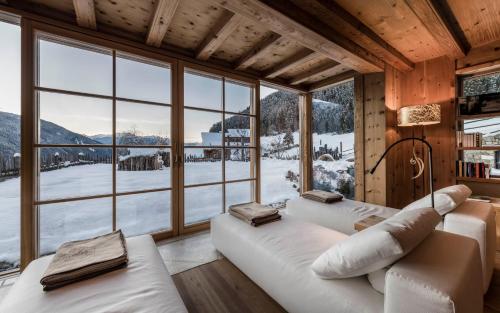 two white beds in a room with a large window at Naturhotel Lüsnerhof in Luson