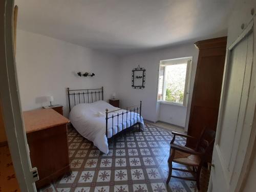 1 dormitorio con 1 cama, 1 silla y 1 ventana en La Galinette, en Arpaillargues-et-Aureillac