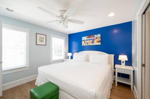 een blauwe slaapkamer met een wit bed en een plafondventilator bij Just steps to Duval- Sleeps 10- Heated Pool House in Key West