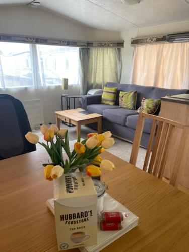 ein Wohnzimmer mit einem Tisch mit gelben Blumen in einer Schachtel in der Unterkunft 3 bedroom holiday home in South Hayling