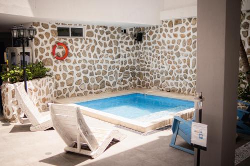 a pool in a room with two chairs and a swimming pool at Hotel Adaz Mediterráneo in Santa Marta