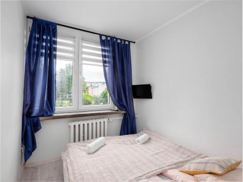 een slaapkamer met een bed en een raam met blauwe gordijnen bij Sweet Honey Mieszkanie w Płocku in Płock