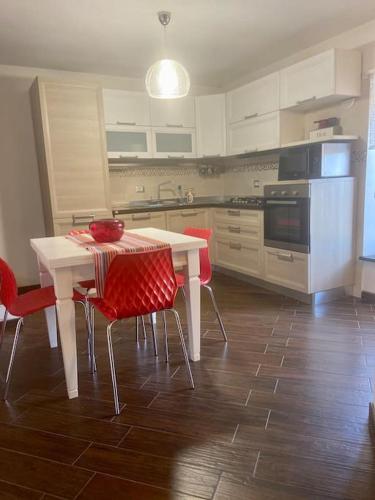 cocina con mesa blanca y sillas rojas en A casa mia, en Acquapendente