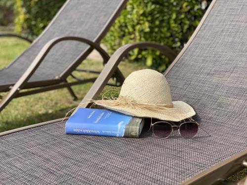 a straw hat and sunglasses and a book on a bench at Casa Paola in Vesta