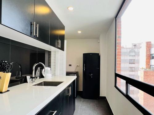 a kitchen with black cabinets and a black refrigerator at Penthouse Chicalá Colombian Experience in Parque Virrey in Bogotá