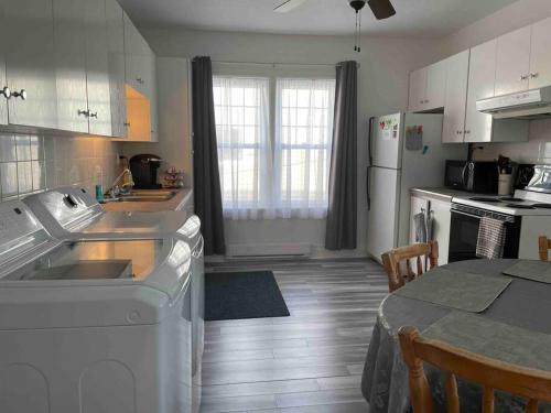 a kitchen with white cabinets and a table and a kitchen with a counter at Le paisible ensoleillé ! beau 51/2 à Drummondville in Drummondville