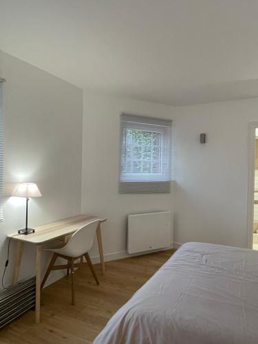 a bedroom with a bed and a desk and a window at Des Fleurs et des Vagues in Villerville