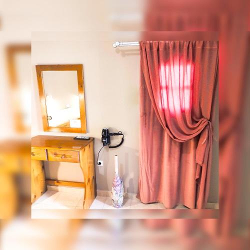 a red curtain next to a desk with a mirror at Le stanze del tramonto di Eleni in Leipsoi