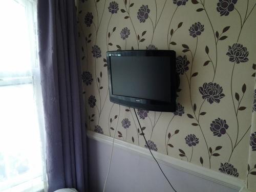 a television on a wall with a floral wallpaper at No. 9 Guest House in Llandudno