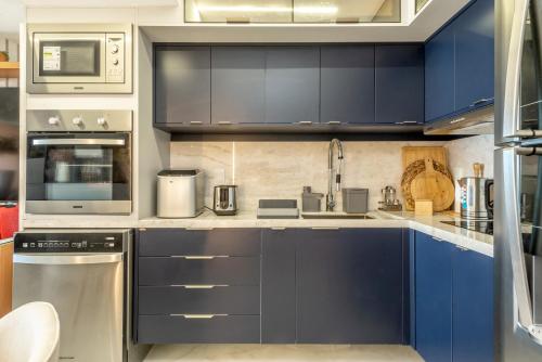 a large kitchen with blue cabinets and appliances at DELUX PRAIA Flats in Natal