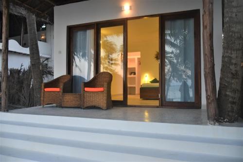 un patio con 2 sillas de mimbre y un dormitorio en Blue Palm Zanzibar, en Bwejuu