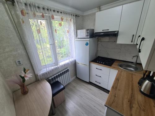 a small kitchen with white cabinets and a sink at Апартамент Плаза in Shymkent