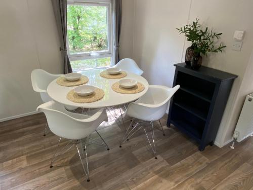 Biały stół jadalny z białymi krzesłami w obiekcie Chalet in de Veluwse bossen w mieście Hoenderloo