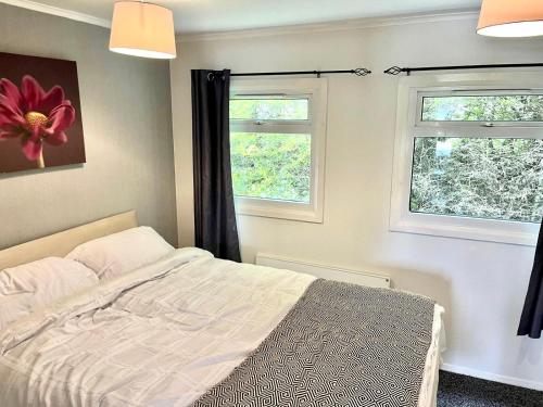 een slaapkamer met een bed en 2 ramen bij Whittams Hot-tub Chalet Retreat in Heysham