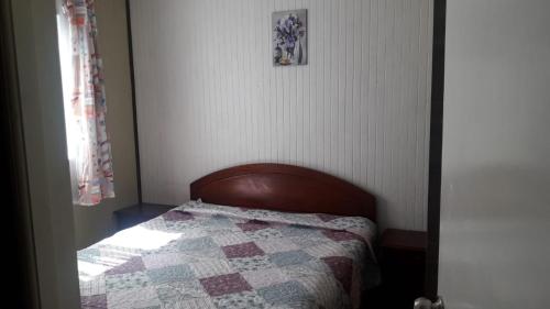 um pequeno quarto com uma cama com uma colcha em Hostal tepual puerto montt em Puerto Montt