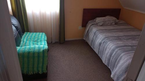 a small bedroom with a bed and a window at Hostal tepual puerto montt in Puerto Montt