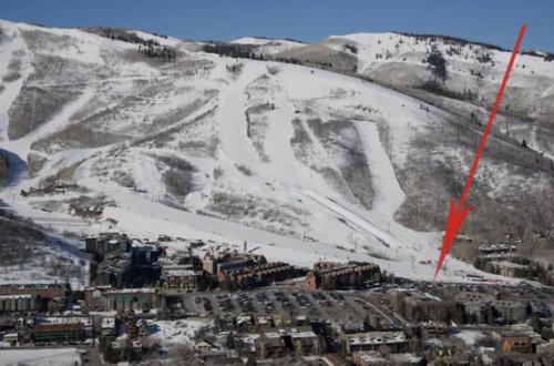 a snow covered mountain with a city and a red arrow at Luxe Park City Mountain Resort Studio in Park City