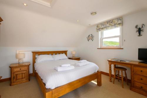 a bedroom with a bed and a desk and a television at Beachcombers Apartments in Newquay