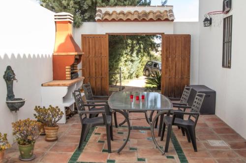 a patio with a glass table and chairs at Casa con piscina caminito del rey in Alora