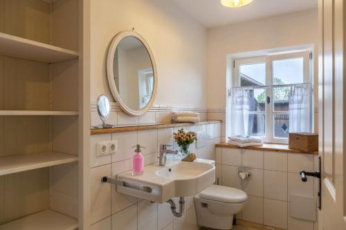 een badkamer met een wastafel, een toilet en een spiegel bij Lisbeth in Rottenbuch