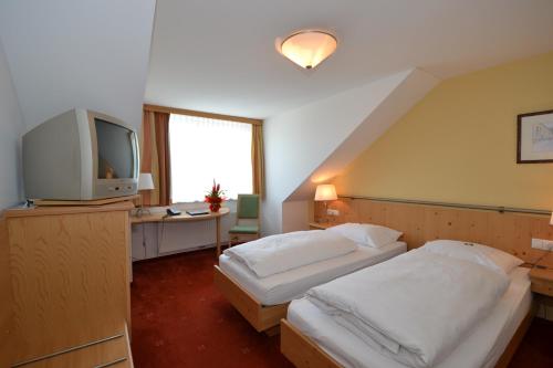 a hotel room with two beds and a television at Hotel Kohlpeter in Salzburg