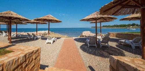 a beach with chairs and umbrellas and the ocean at Apartman Hana in Brtonigla