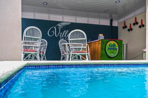 a pool with chairs and a table next to at Villa De Cruz - Deluxe Suite in Scarborough