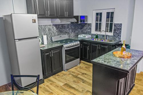 a kitchen with black cabinets and a white refrigerator at Villa De Cruz - Deluxe Suite in Scarborough