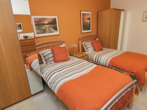 two beds in a room with orange walls at Orchard Lodge in Warkworth
