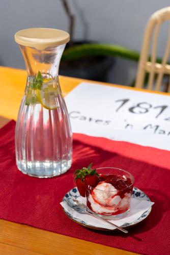 a glass vase and a plate with a strawberry on a table at 1812 Caves 'n Mansion in Karterados