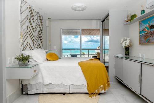 a bedroom with a bed and a view of the ocean at DELUX PRAIA Flats in Natal