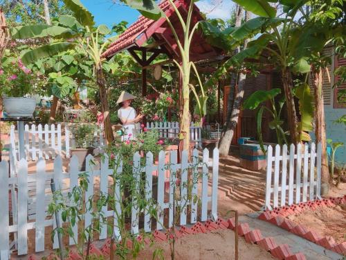 a woman standing behind a white picket fence at Hue Lotus Homestay in Hue