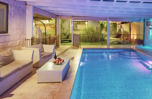 a swimming pool with white furniture next to a swimming at מור ולבונה - וילה מהממת ומפנקת למשפחות בגליל in Sifsufa