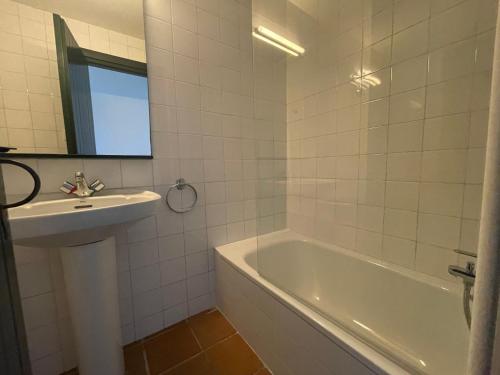 y baño con lavabo, bañera y espejo. en ERMITA by SOM Menorca, en Fornells