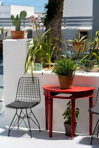 a red table and two chairs and potted plants at 1812 Caves 'n Mansion in Karterados