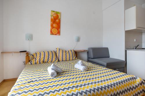 a bedroom with a bed with a yellow and blue blanket at Apartments IN in Neum