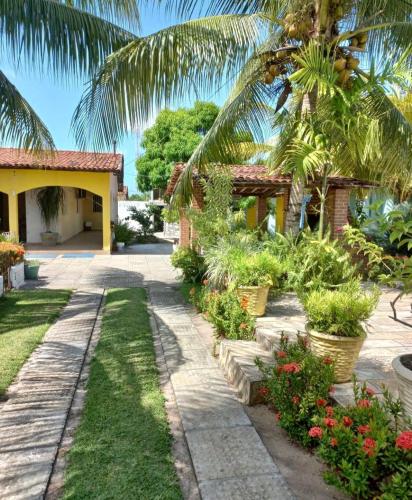 un jardin avec des palmiers et des fleurs devant une maison dans l'établissement RECANTO DOS LIRAS, à Goiana